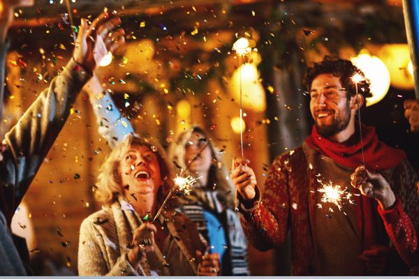 People celebrating with sparklers and confetti during a festive nighttime gathering.